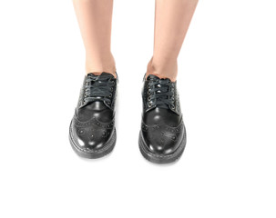 Legs in stylish black brogue shoes on light background
