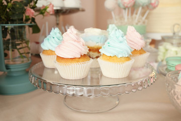 Glass stand with beautiful tasty cupcakes on table