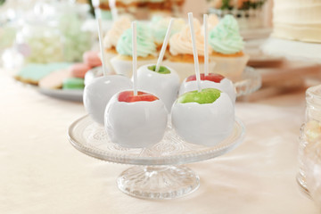Vintage glass stand with candy apples on table