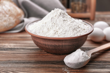 Fototapeta na wymiar Bowl and spoon full of white flour on wooden table