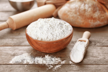Fototapeta na wymiar Bowl and scoop full of white flour on grey wooden table