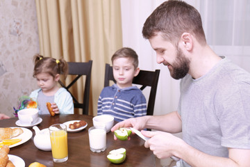 Young father with children having breakfast in kitchen