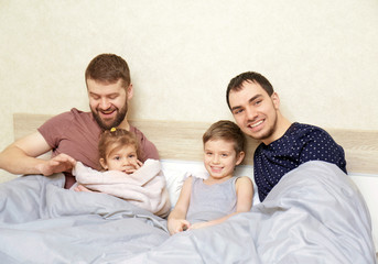 Fototapeta premium Male gay couple with children resting in bed at home