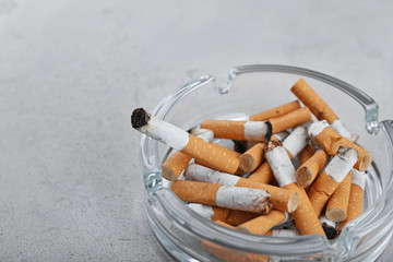 Cigarette butts in ashtray on light background