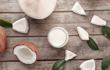 Glass of coconut milk with nuts on wooden background