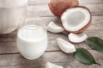 Glass of coconut milk with nuts on wooden background