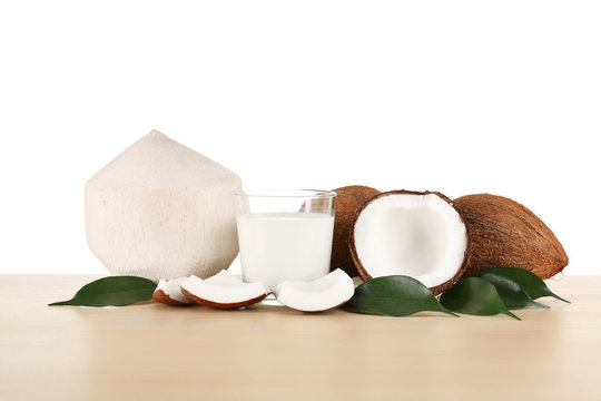 Glass of coconut milk with nuts on white background