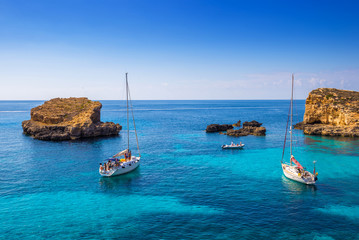 Comino, Malta - Sailing boats at the beautiful Blue Lagoon at Comino Island with turquoise clear...
