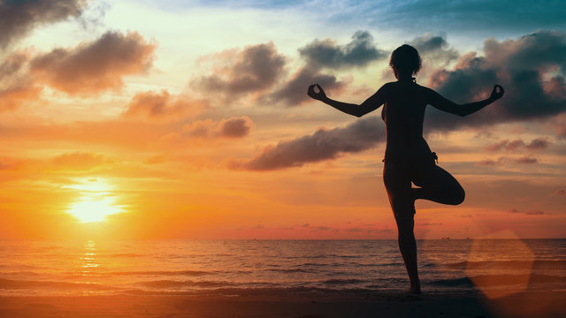 Surreal yoga silhouette of woman on the Sea beach.