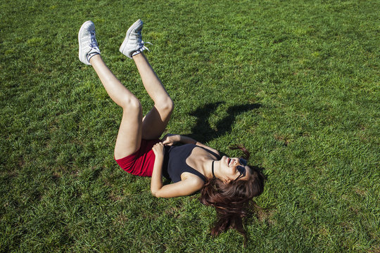 Cheerful young woman lying on grass