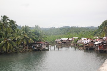 Fototapeta na wymiar Houses by the riverside, Southern Philippines Houses on stilts in a fishing village in Lianga, Surigao del Sur, Philippines
