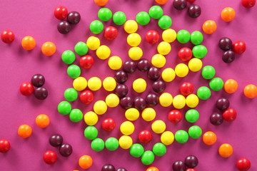 Colorful candies in shape of star on color background