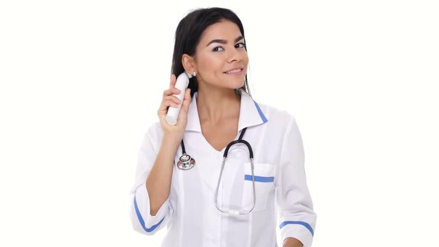 Smiling woman doctor showing and using temperature measuring device near temples isolated