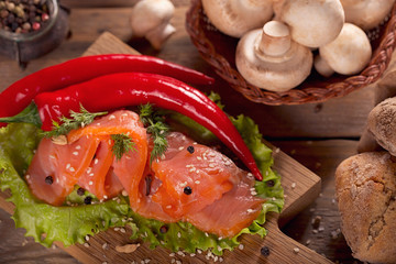 Slices of smoked salmon with dill, chili pepper, mushrooms and bread