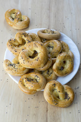 Baked fresh pretzels on white plate, heart and twisted knot shapes, covered with poppy seeds salt and caraway seeds