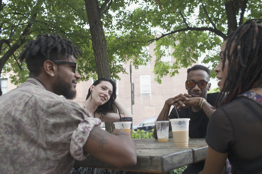A group of friends having a conversation at a picnic table.