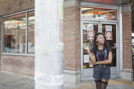 A young woman waiting outside a store.