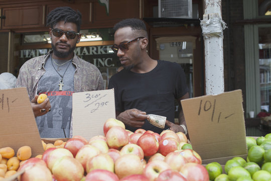 Two young men at a fruit stall.