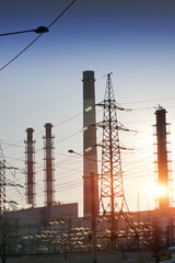 Industrial landscape. Sunset over the power line and pipes of combined heat and power plant