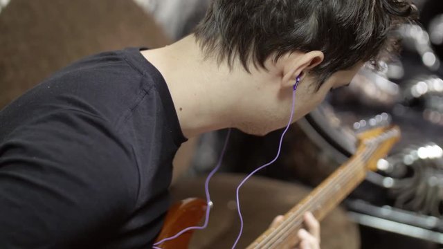 Man in headphones playing an electric guitar warming up before a live show a musical performance, indie rock, pop rock.