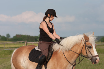 A young woman riding a horse Haflinger