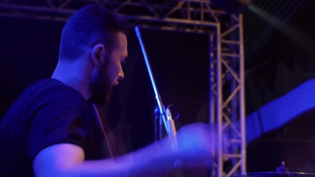 Drummer from the rock band professionally plays the drums on stage, with the light of the soffits, indie rock, pop rock, live show.