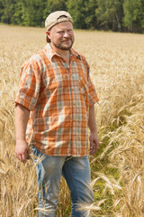 Naklejka na ściany i meble Farmer in cap standing at field