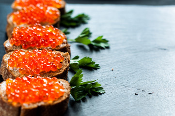 Red caviar on slate background.