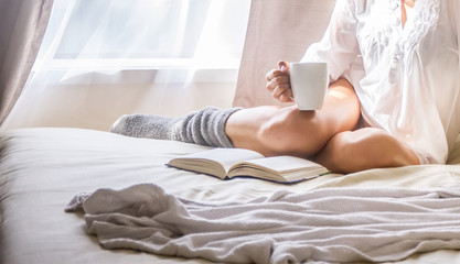 Young woman in bed while reading a book