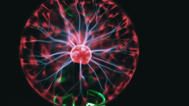 Closeup view of plasma ball with moving energy rays inside on black background