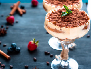 luxurious Tiramisu cake in a glass on a dark background decorated with mint