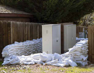 Sandbags stacked around some electrical panels in preparation for a flood.