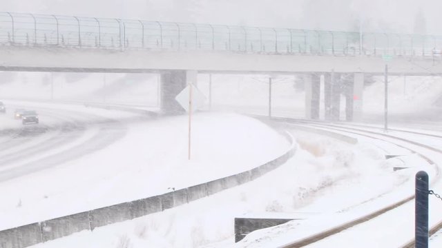 Camera pan on cars driving on freeway during snow storm.