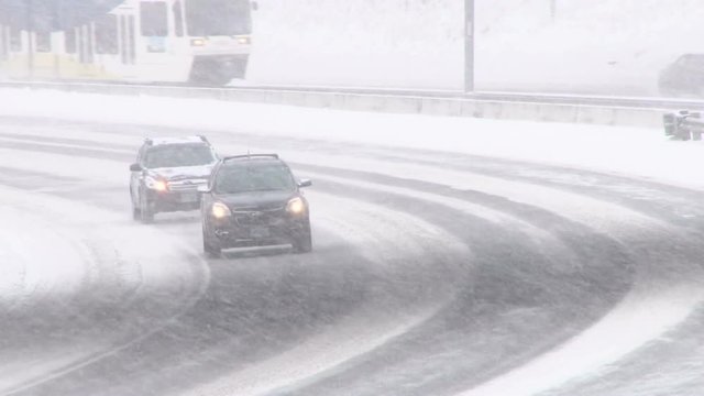 Traffic driving along freeway during intense snow storm.