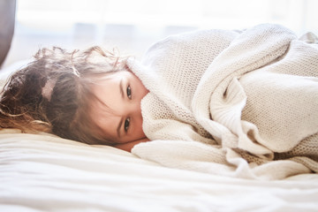 indoor portrait of young child girl wrapped in blanket