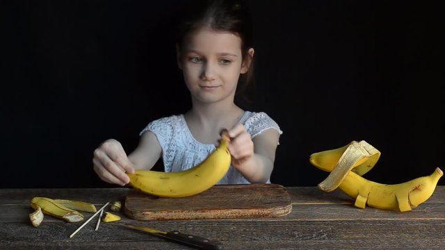 Girl doing a toy from bananas. Black background
