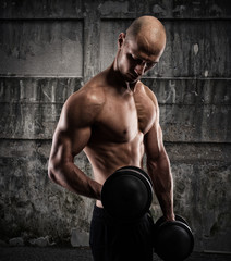 Fototapeta na wymiar Athletic man training biceps on grunge background