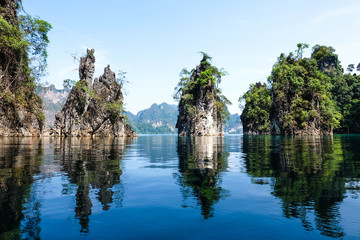 Three moutains island with green tree and blue sky at Ratchaprapa Dam in Thailand, mirror or shadow of water and double image of mirage concept © amperespy