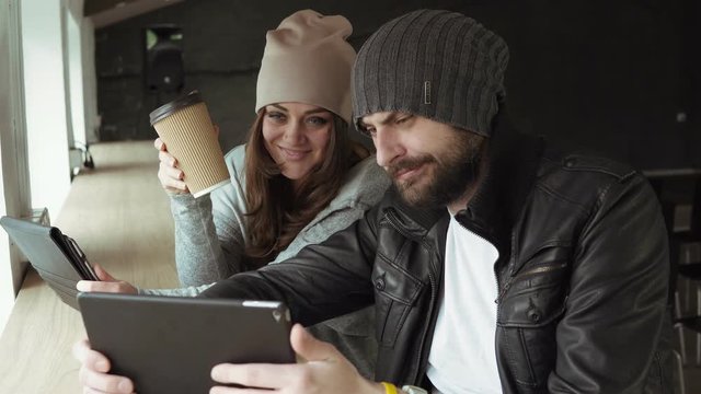 Work meeting in creative office. Young man and woman using a tablet to take pictures and having fun. Conference call. Shot in 4k