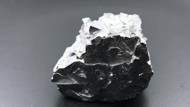 Rotating Galena, a silver mineral, with black background.