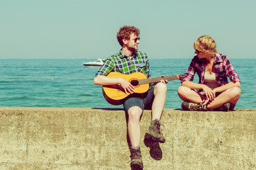 Young man playing guitar to his girlfriend outdoor
