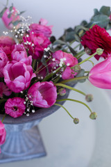 Pink ranunculus and pink tulips arranged in iron vase