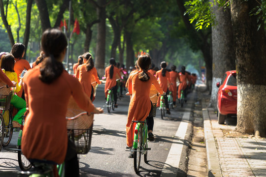Vietnamese girls wear traditional long dress Ao Dai cycling on Hanoi street