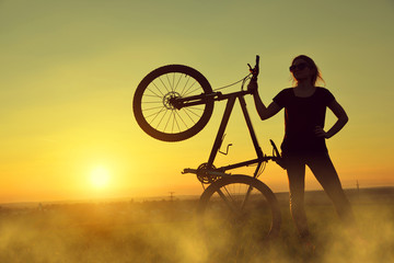 Naklejka premium Girl on a bicycle in the sunset.