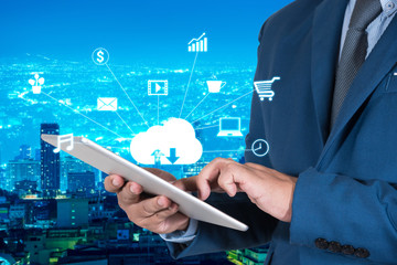 businessmen in blue suite using internet of things on mobile or tablet with night modern city background