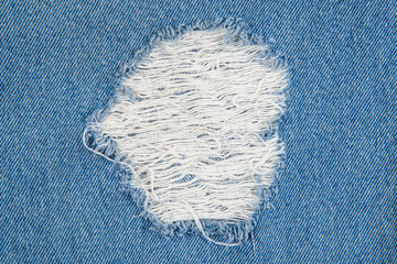 Fototapeta na wymiar blue jean texture with a hole and threads showing