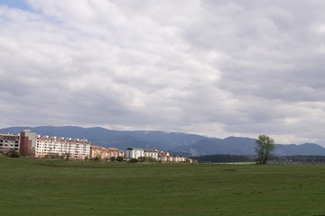 Fototapeta na wymiar Meadow with trees and views to mountains and town. Slovakia