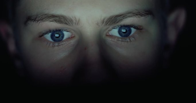 12 years teen puberty eyes looking at the monitor in a dark room,surfing the Internet, close-up