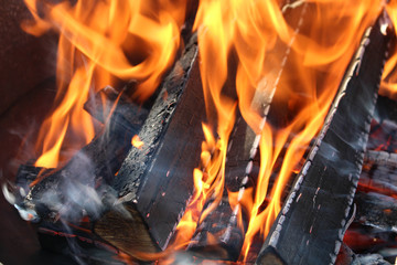 Charred wood and bright flames on dark background