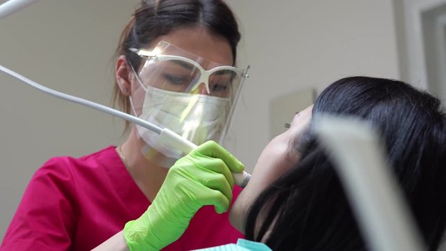 Woman at the dental hygienist getting professional tooth whitening and ultrasound cleaning. Shot in 4k